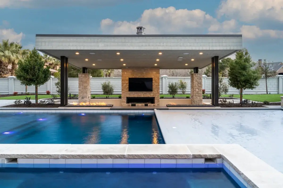 Automatic cover partly closed over a pool beside an outdoor pavilion at dusk