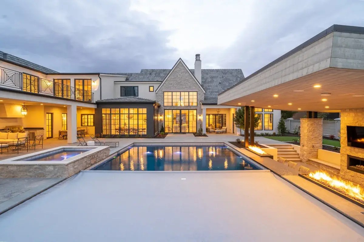 Automatic pool cover with a spa: raised stone spa beside a pool with the cover partly open
