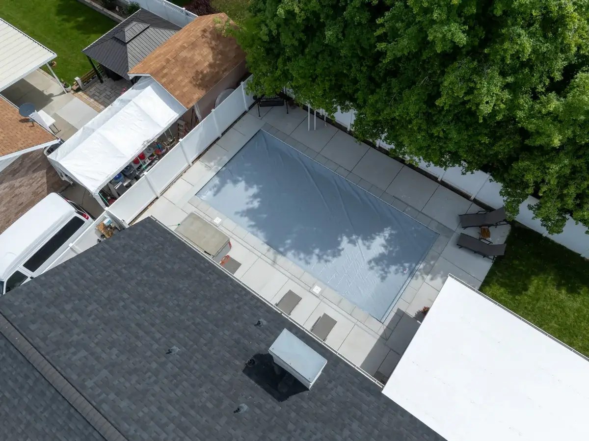 Aerial view of an automatic pool safety cover fully closed over a backyard pool