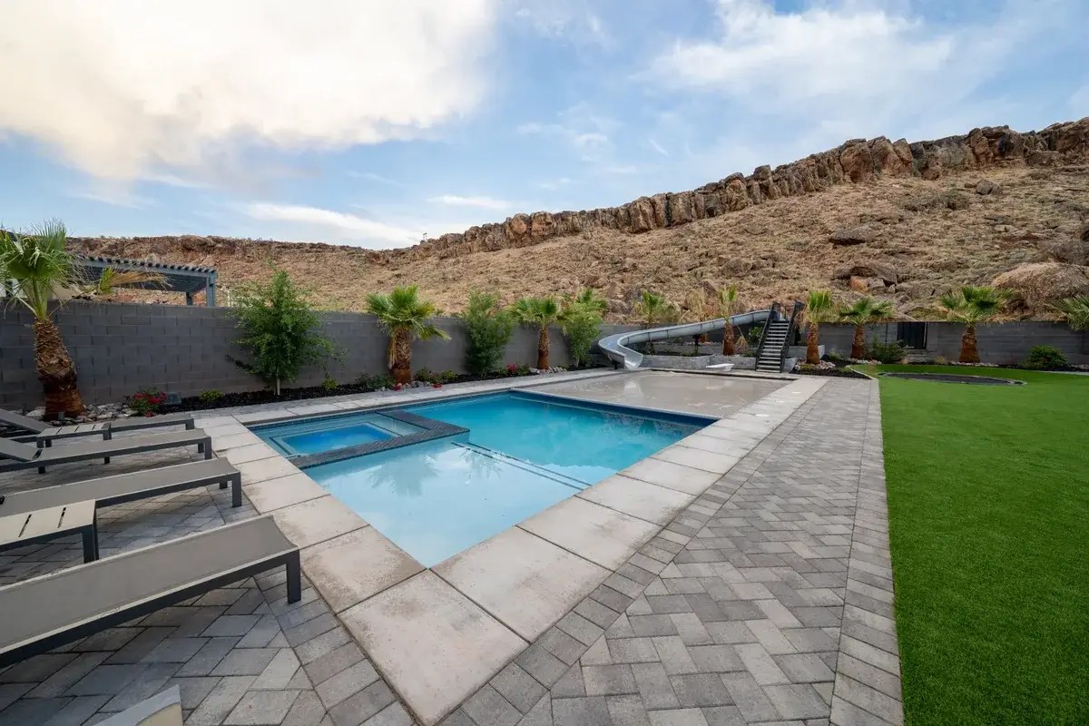 Corner square spa inside a pool with the automatic cover open at the far end