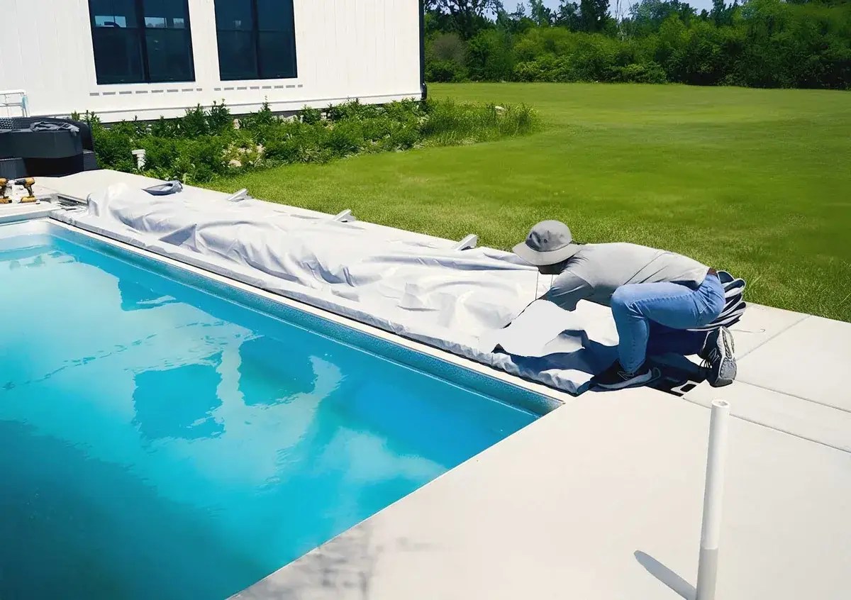 Installer fitting an automatic pool cover at the cover end of a rectangular pool