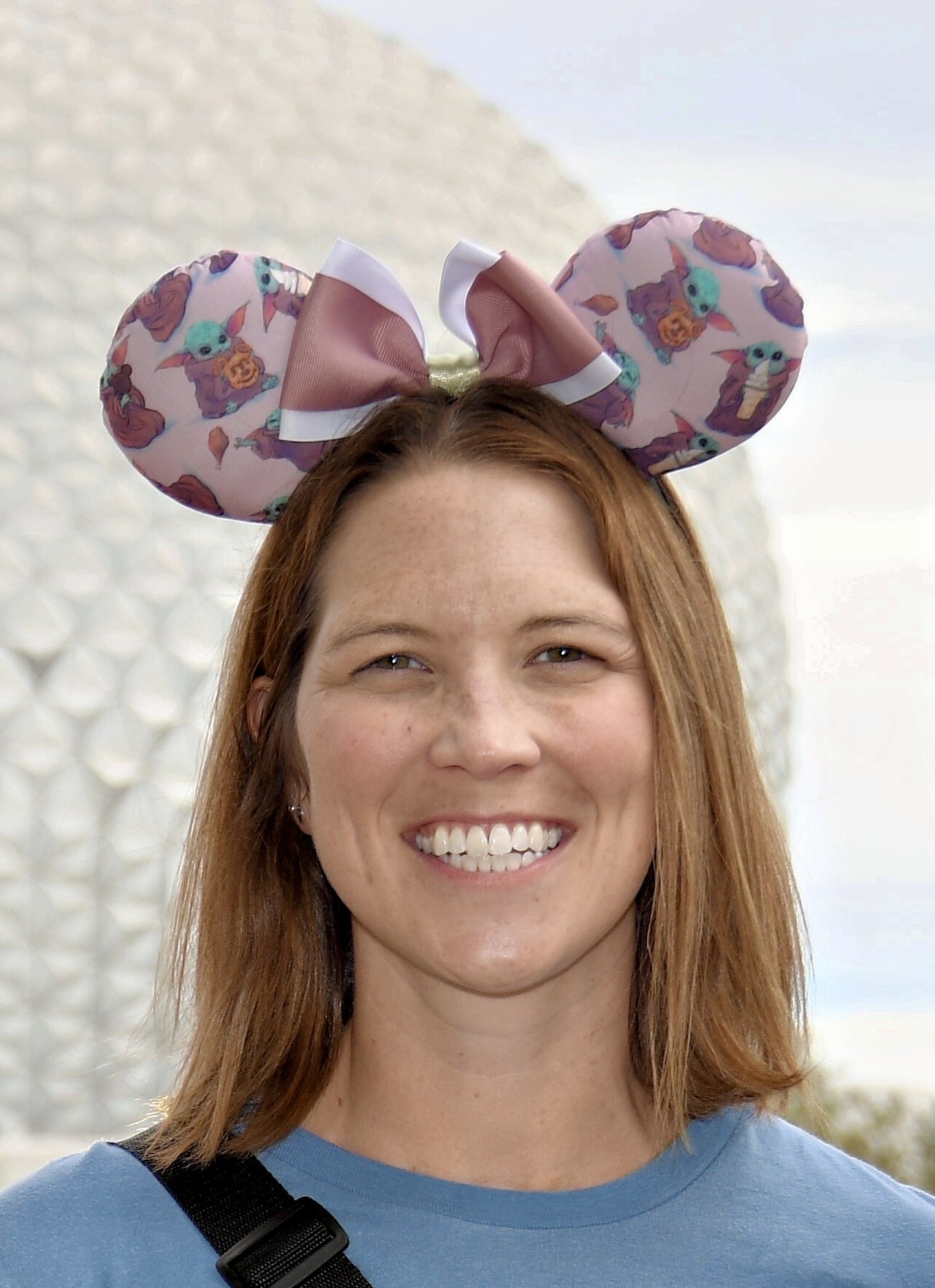 a selfie of a travel agent wearing Disney mouse ears standing in front of Spaceship Earth at Epcot