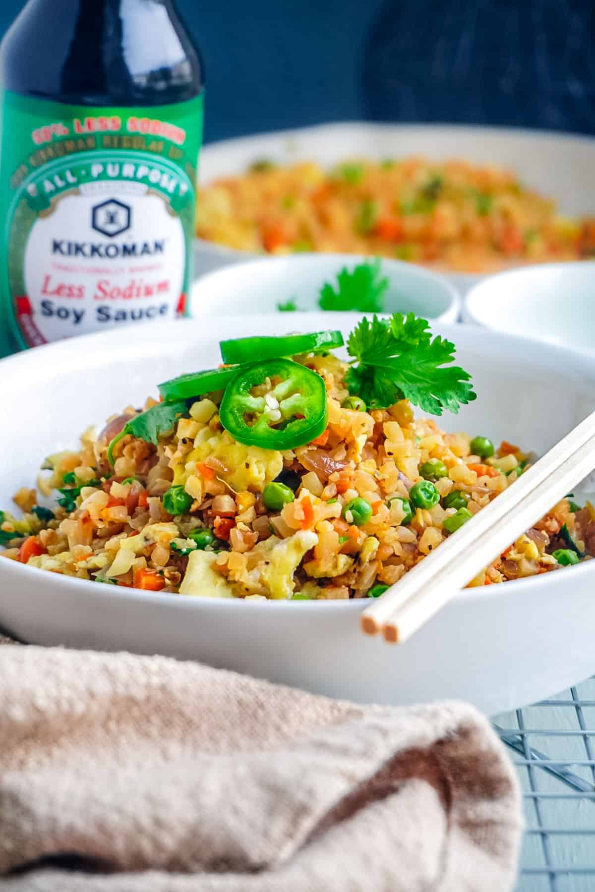 The finished Cauliflower Fried Rice in a white serving dish with chopsticks.