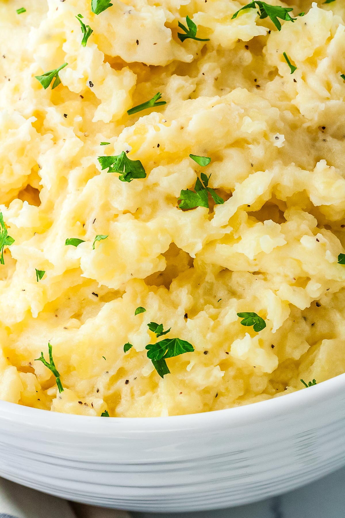 Fluffy cottage cheese mashed potatoes topped with chopped parsley, showing a creamy, buttery texture in a white serving bowl.