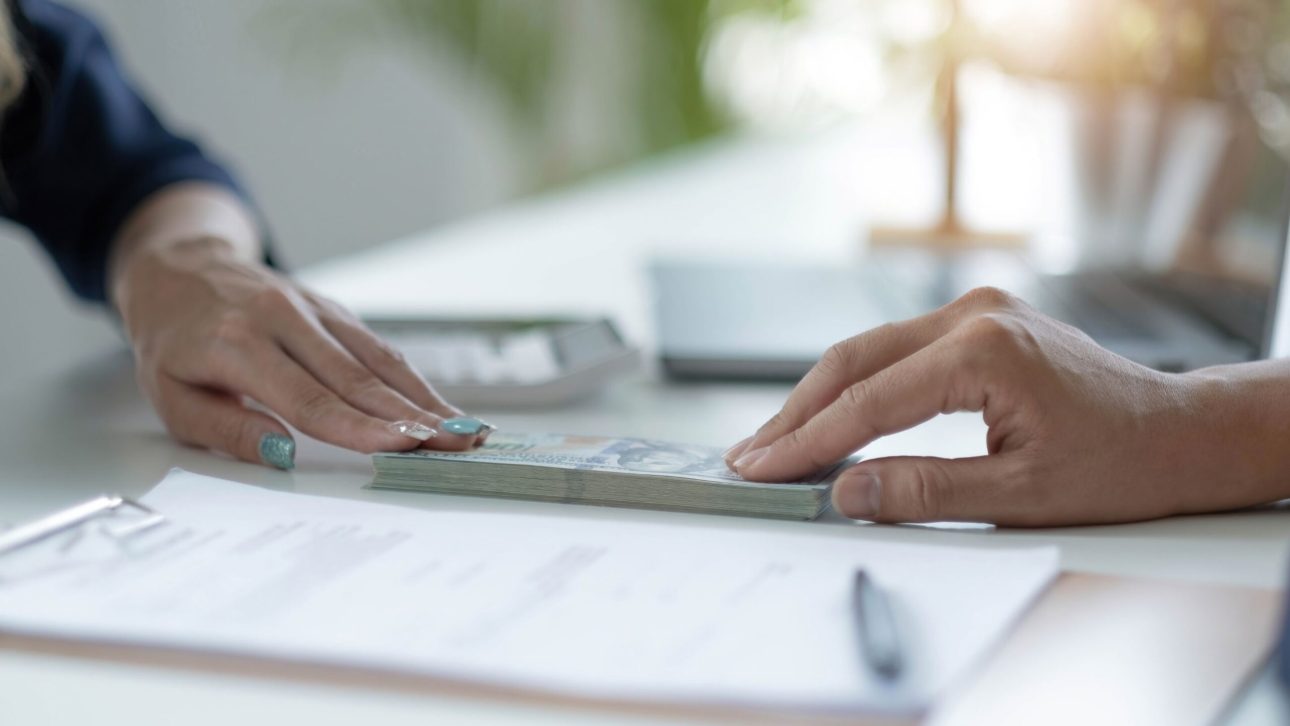 a woman and a man are exchanging money. Their hands are visible, but the rest of their bodies are not in the frame.