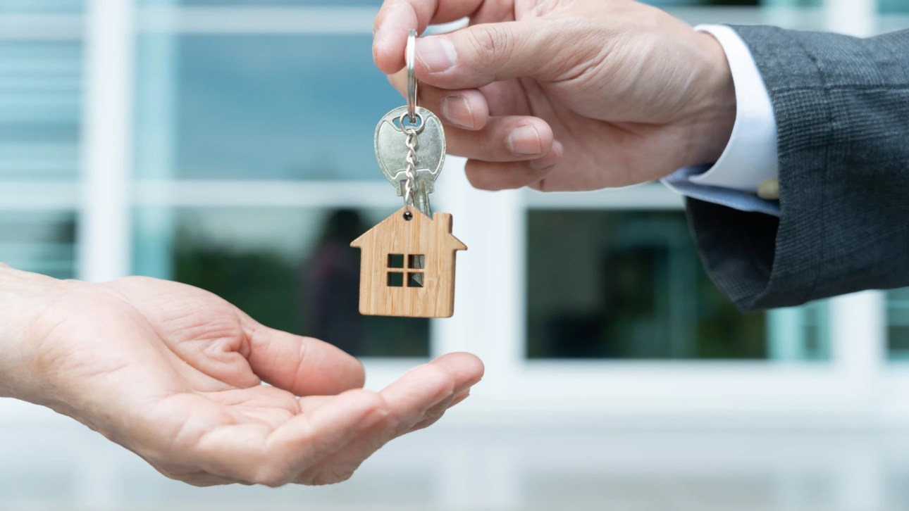 Defeasance clause- close up of a suited person hand handling a house keys to another person.