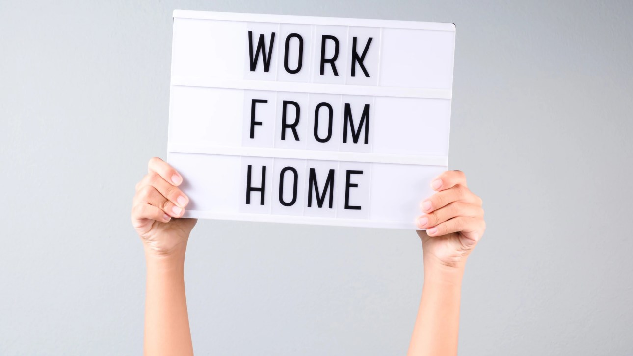 Can I work from home as a real estate agent?- hand holding high a board with the words work from home