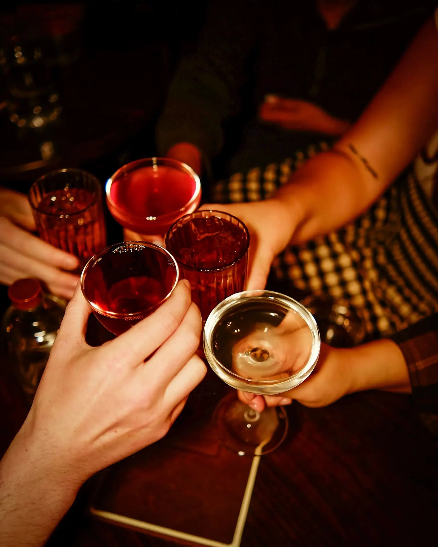 Hands come together with drinks to cheers