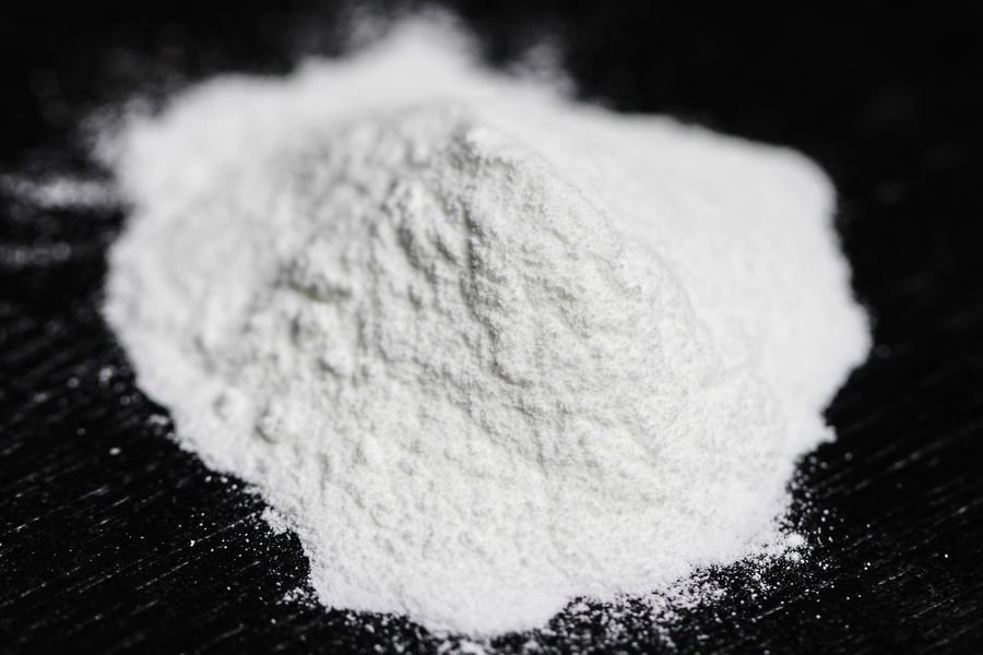 P&oacute; branco do fermento qu&iacute;mico em close sob fundo escuro