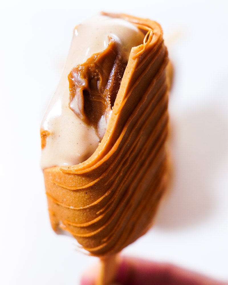 Picol&eacute; de Biscoff Cremoso com Chocolate Branco Caramelizado mordido mostrando o recheio.