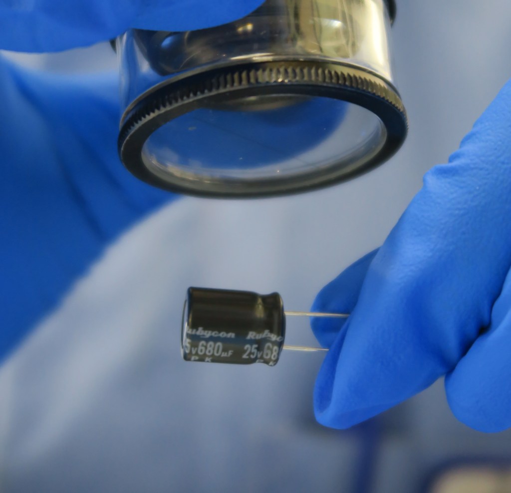 Person checking the details on a component using a magnifying glass
