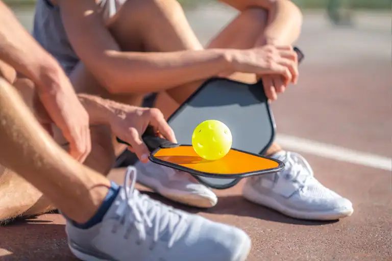 Person testing hearing aid with a tablet and yellow ball outdoors.