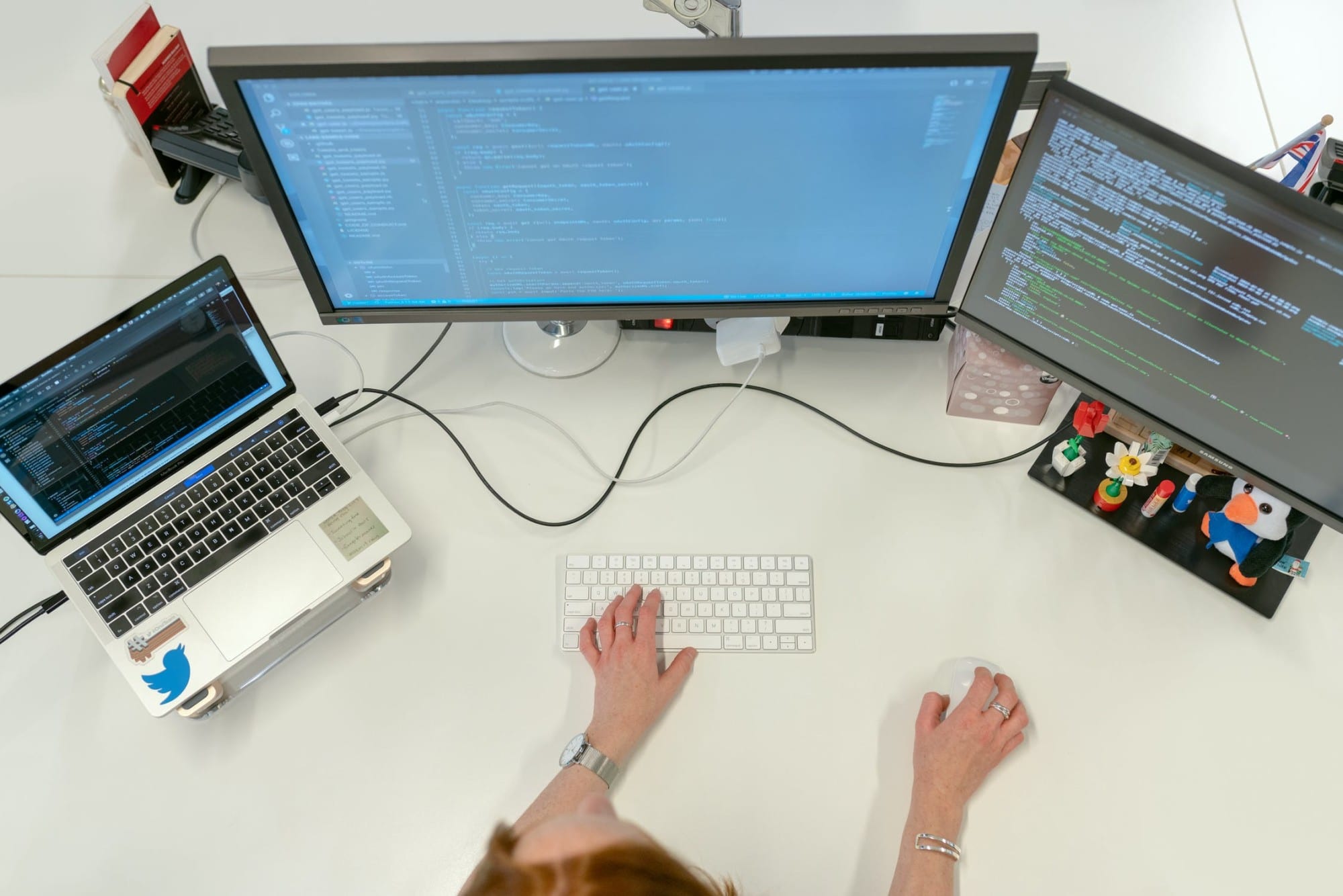 a website developer working on a laptop with two external monitors