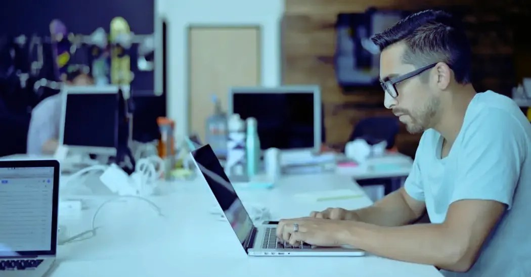 a young man working on a laptop in an office