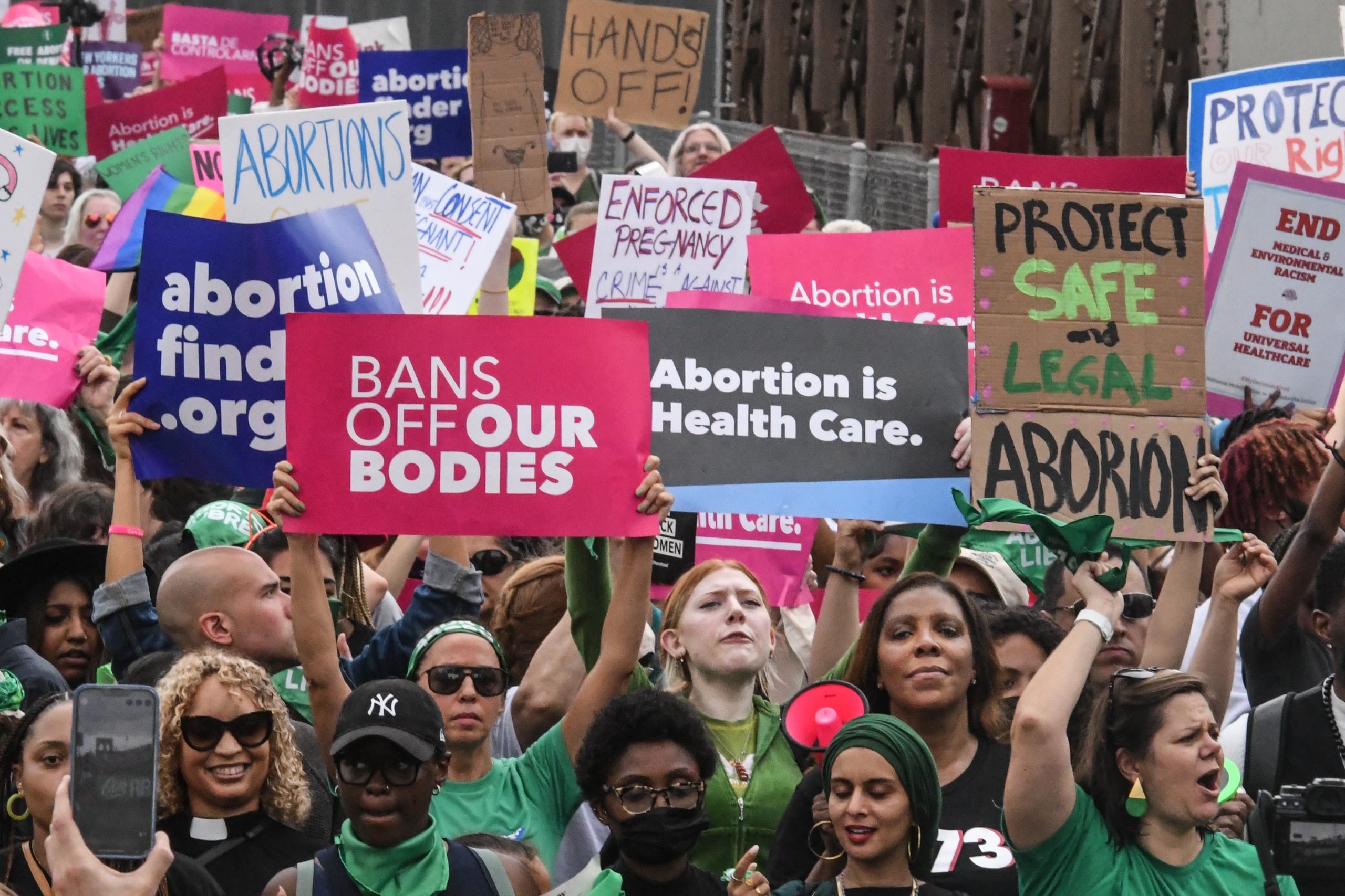 pro-choice protesters hold signs reading "bans off our bodies" and "abortion is health care"