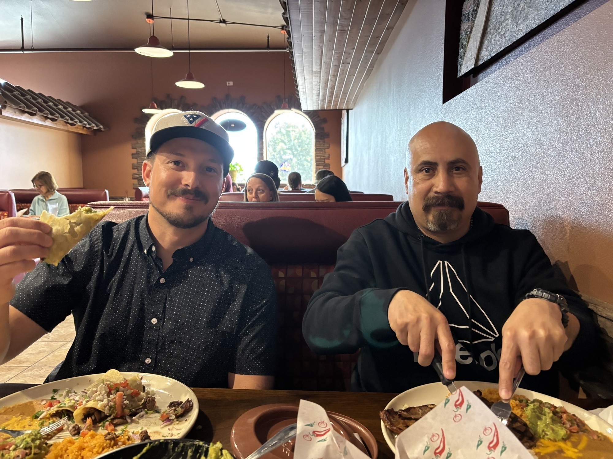 An image of two men sitting in a booth at a Mexican restaurant.
