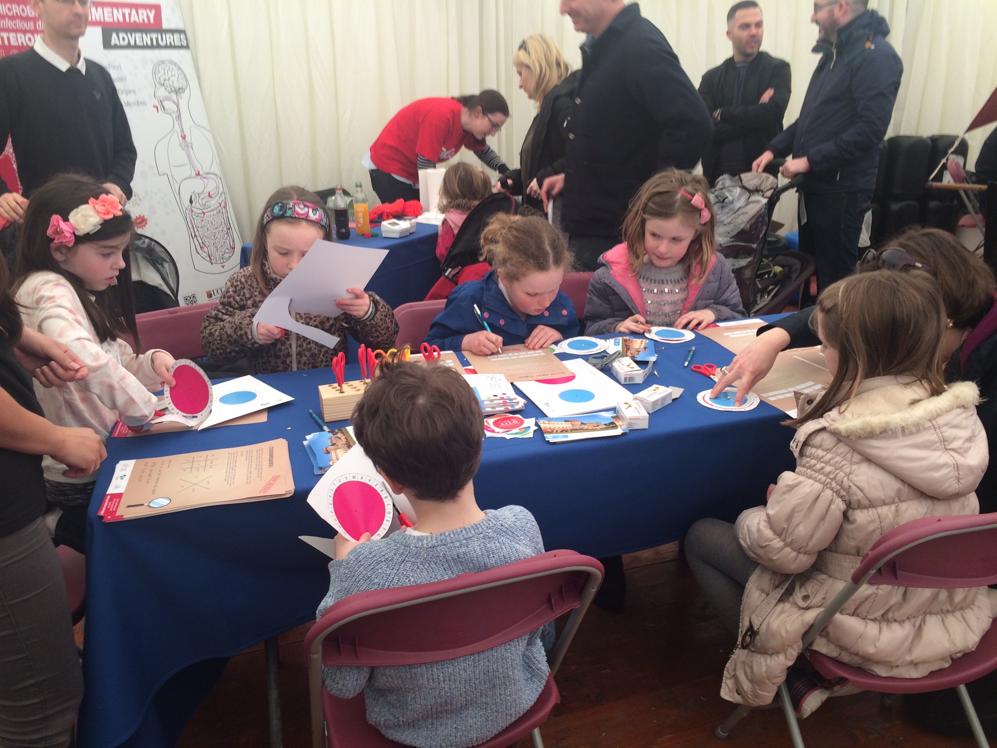 Children sitting at table cutting out circular shapes on card