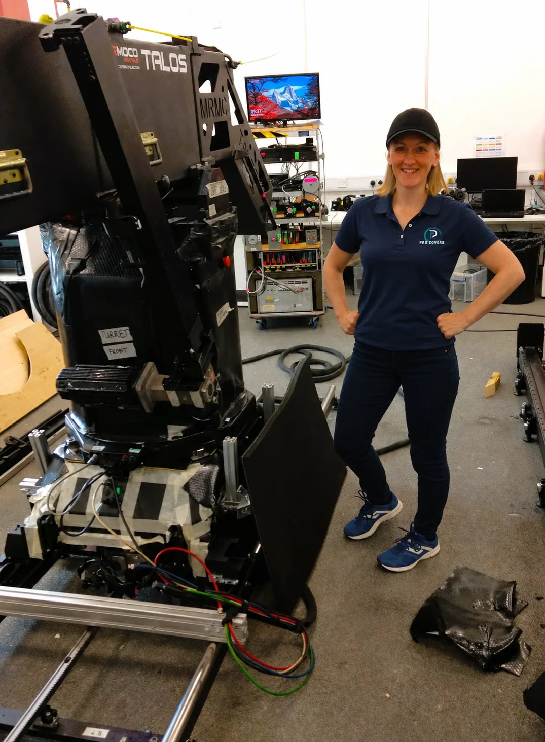 Lucy, ProCovers founder, wearing a branded navy polo beside Talos equipment