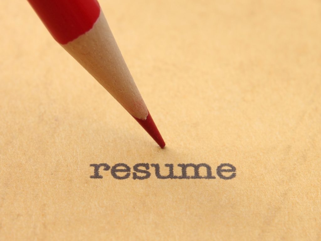 Red Pencil pointing at the word resume in typewriter type