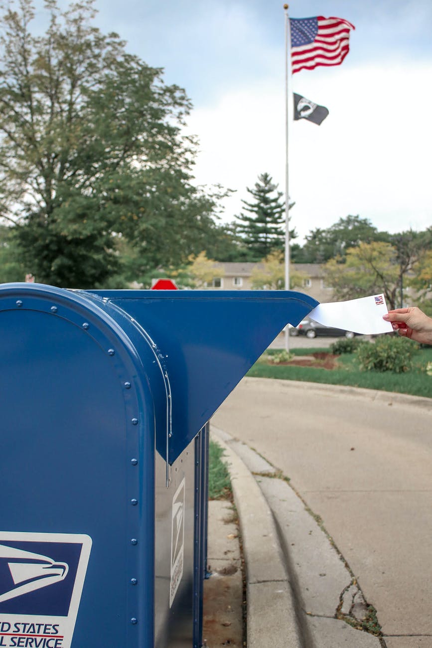 crop person putting envelope in mailbox on street