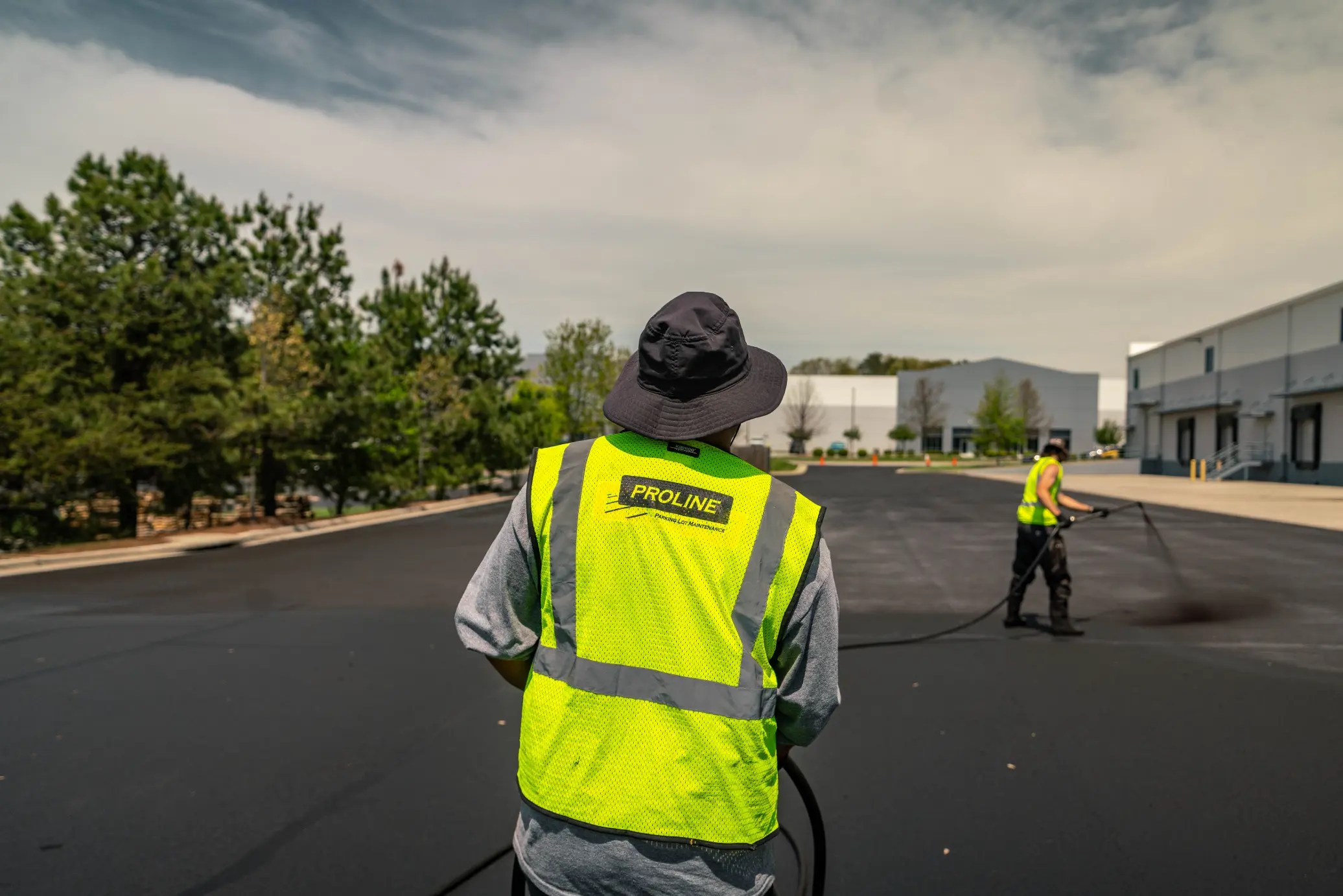 Workers applying sealcoat to pavement