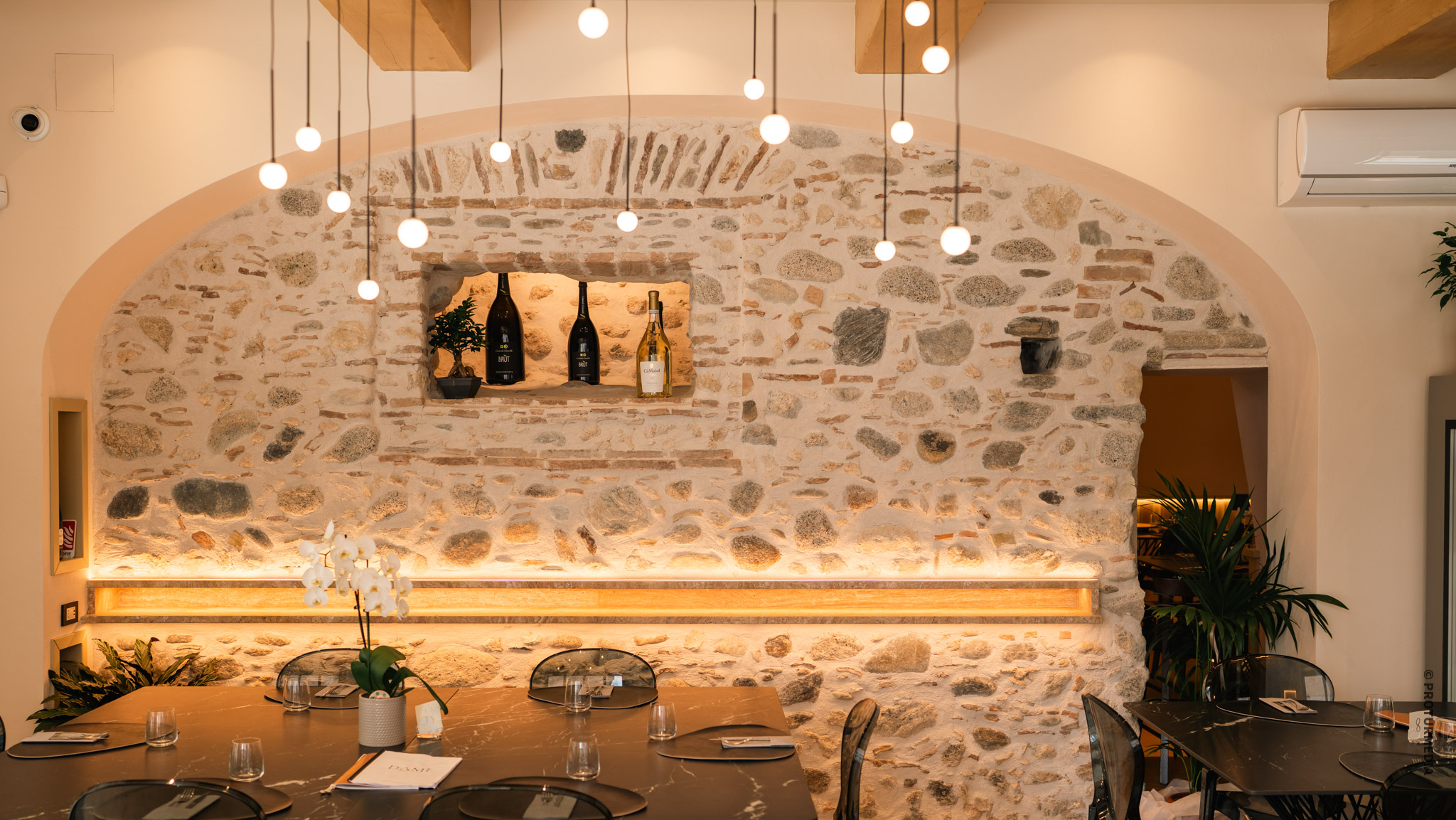 Sala di ristorante con pareti in pietra e lampade a sospensione