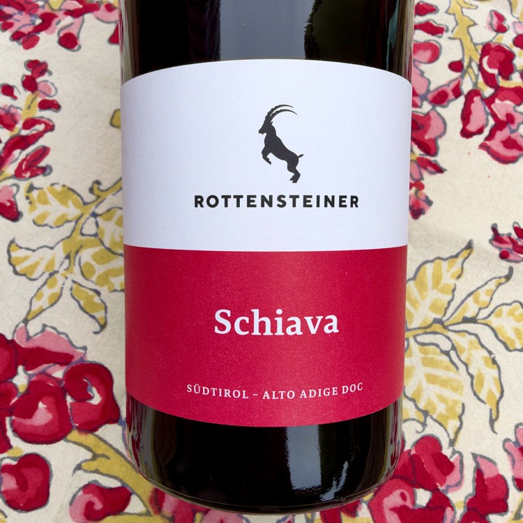 Photo of 2025 Hans Rottensteiner Schiava, Südtirol-Alto Adige DOC bottle label with red and yellow flowers in the background