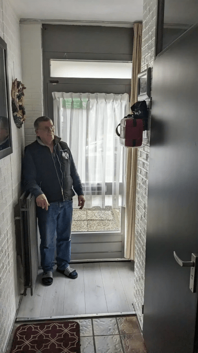 Man standing near a red AED case mounted in a hallway.