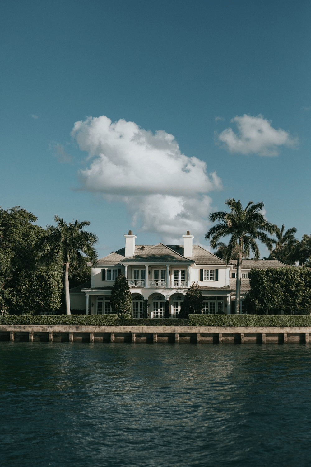 Luxurious waterfront property with elegant architecture and lush landscaping against a clear blue sky.