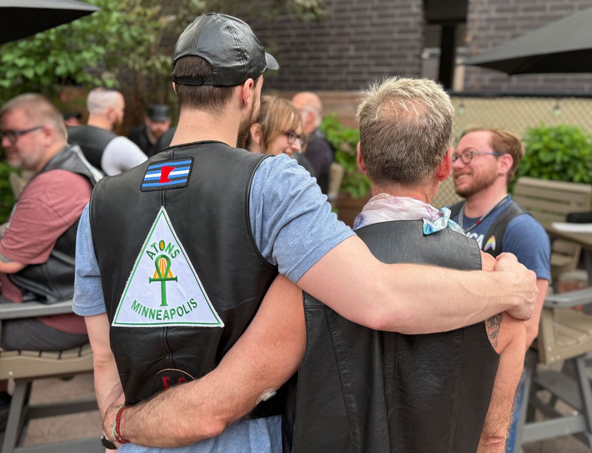 Two people embracing at an Atons bar night at the Eagle, seen from behind in leather vests