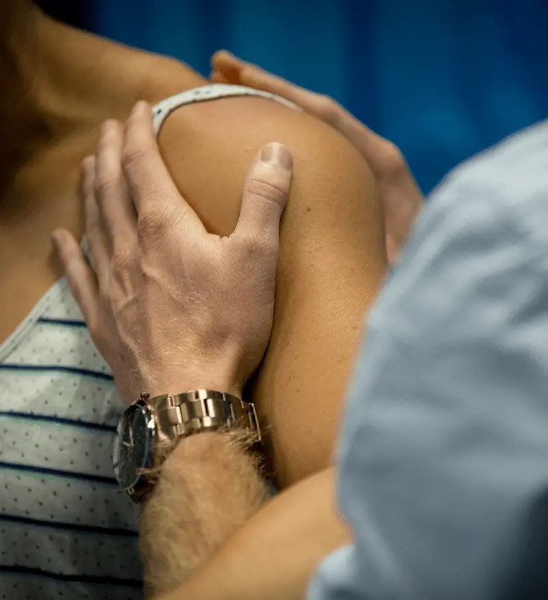 A QSMC client receiving treatment on their shoulder by a Physiotherapist