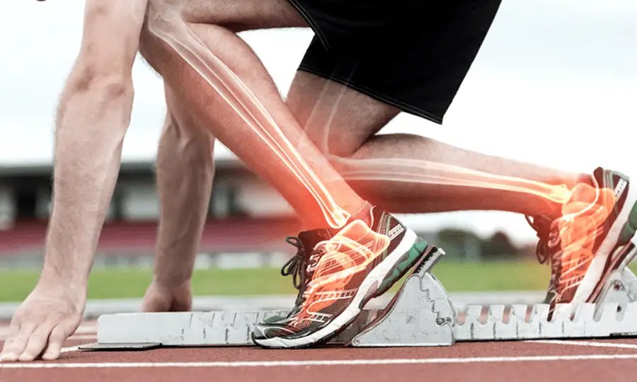 Image of an athletic runner in the starting blocks with the lower limb bones highlighted
