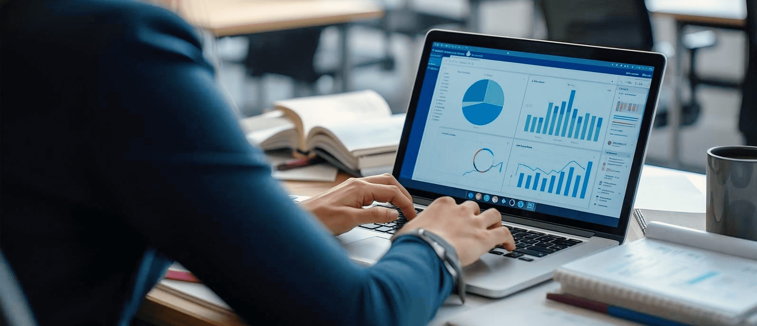 A person working on a laptop displaying financial data analysis dashboards with charts, graphs, and performance metrics in a modern office setting.