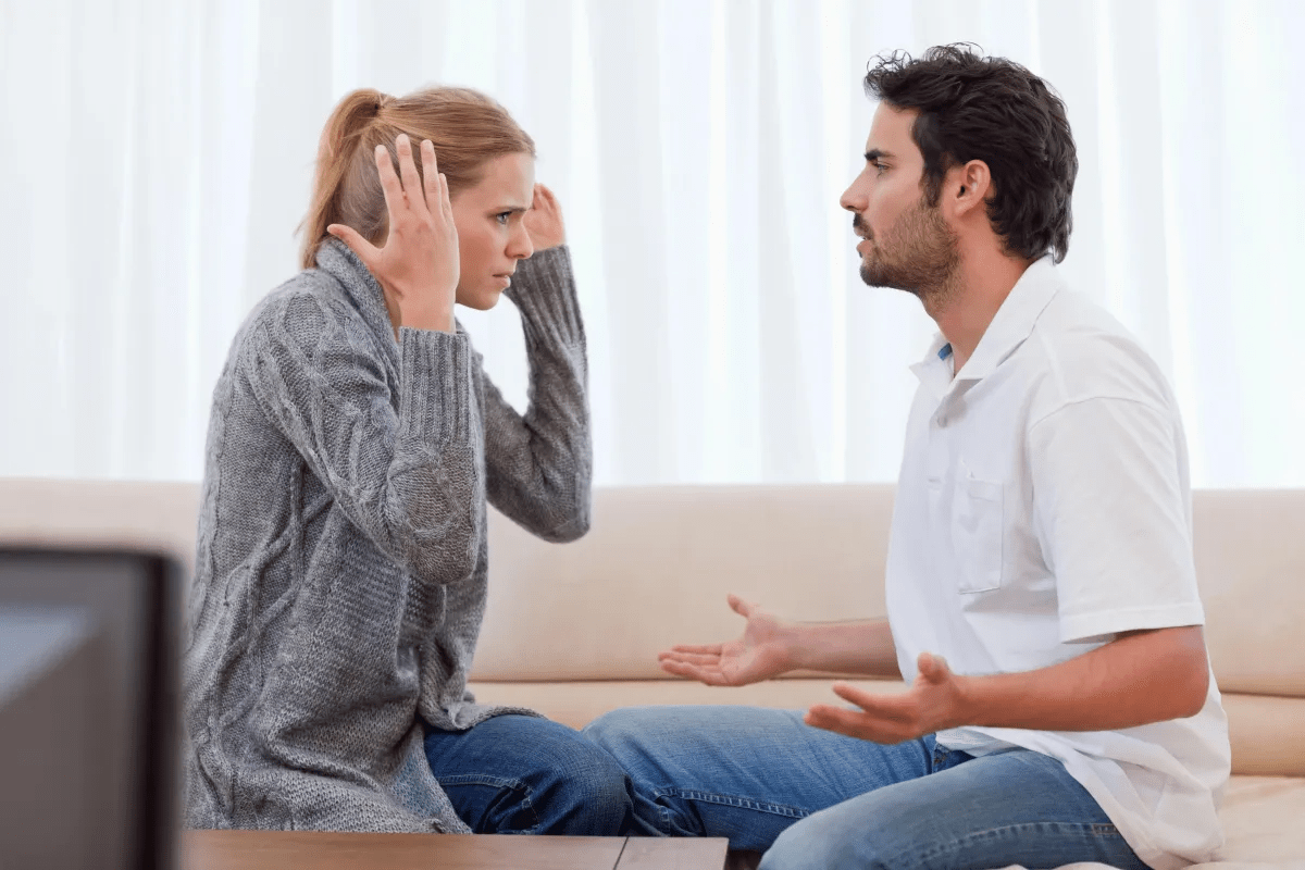 A couple is having a heated discussion or argument while sitting on a couch.