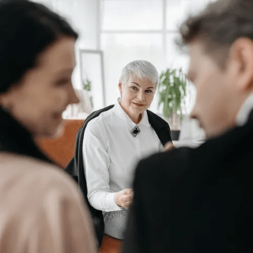 Three people are engaged in a serious conversation, possibly in a counseling setting.