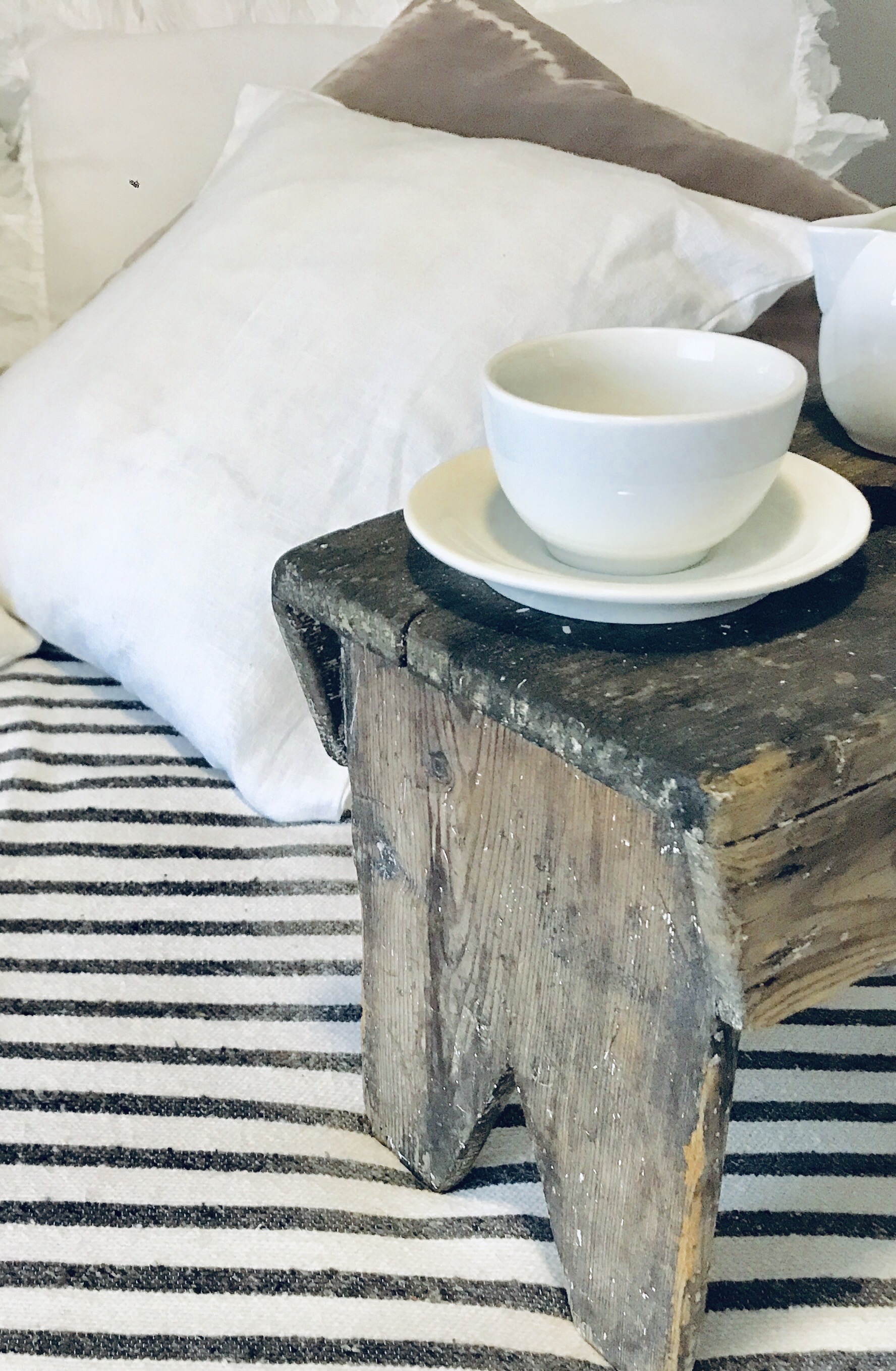 Rustic wooden stool with white teacup and saucer