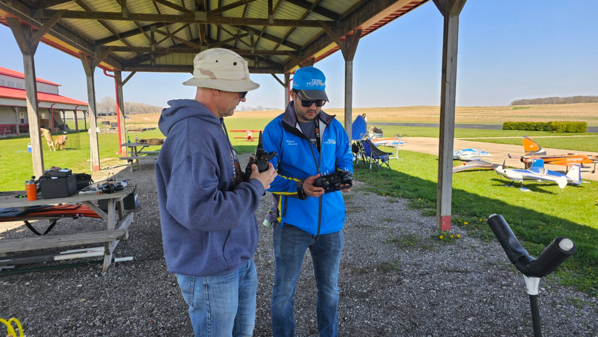 Two RC pilots comparing transmitters at the flying field