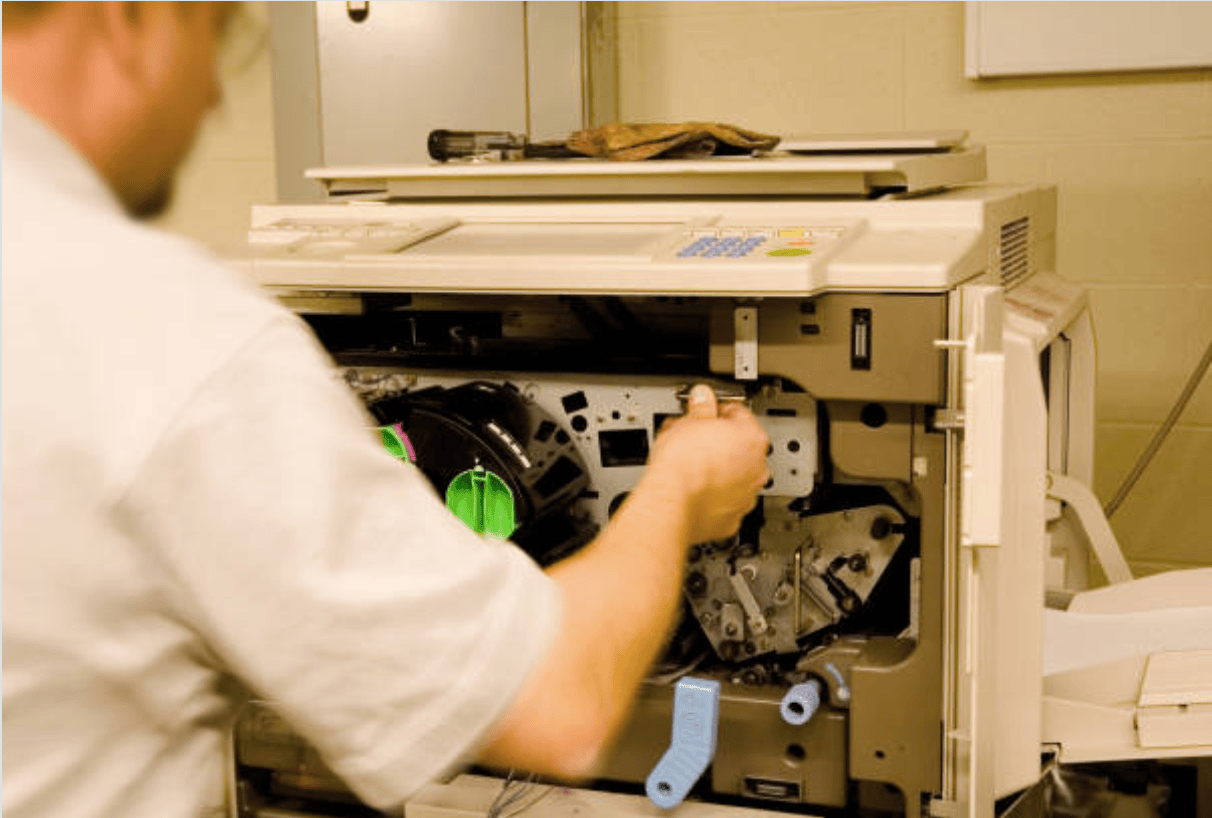 RDI Solutions technician repairing an office copier with the front panel open