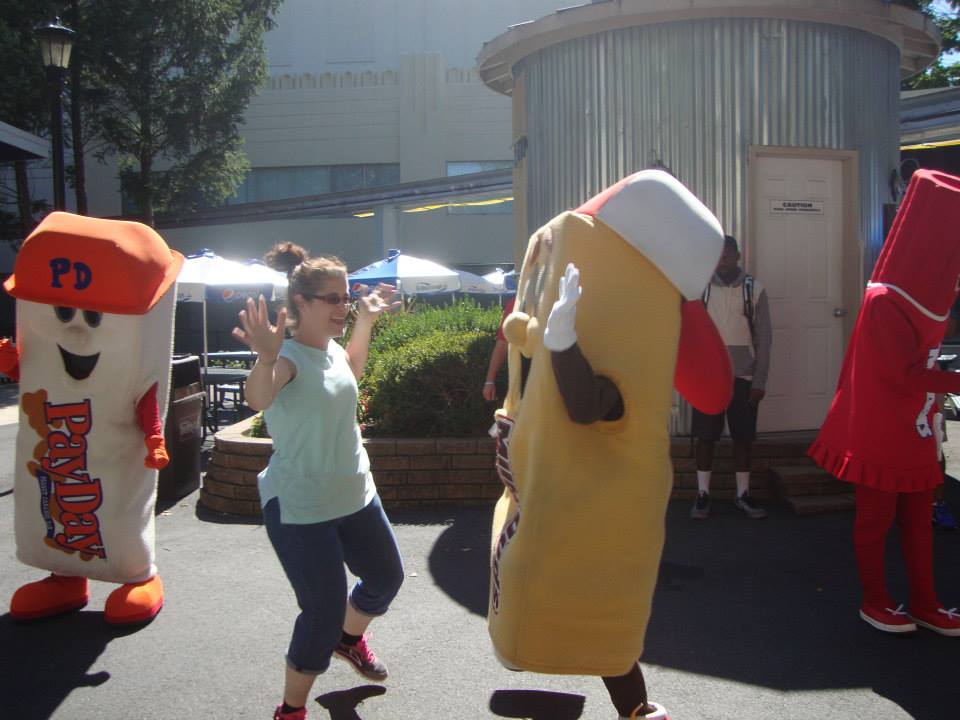 An image of a woman dancing with Hershey mascots at Hersheypark