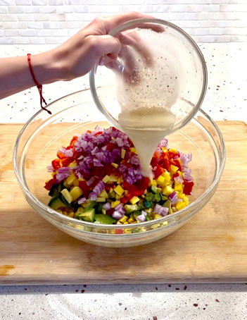 Pouring the lime dressing over the corn salad