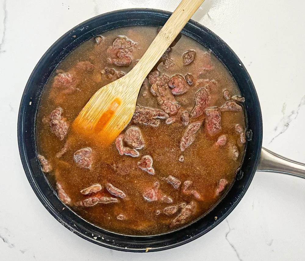 Adding beef broth to the beef
