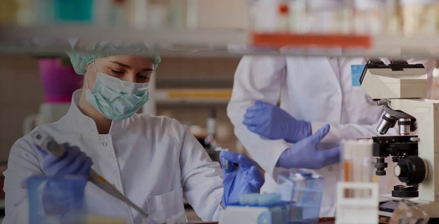 Lab technicians analyzing samples under a microscope