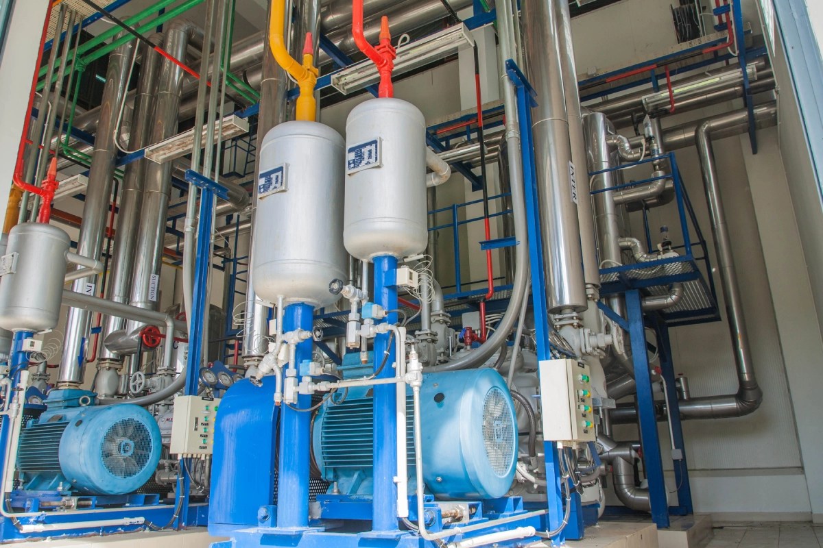 Industrial equipment with blue machinery and metallic pipes in a facility, integrated with industrial thermal energy systems. Various colored pipes are connected to the system.