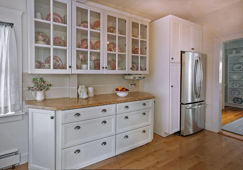 White kitchen cabinets with glass-front doors showcasing interior shelving and decor