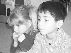 Kirsten Nichols and Humberto Vasques watch as their teacher counts pennies from a jar.
