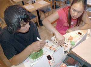 From left, Pisal Pompaladisai and Patcha Pompaladisai share a bite at Rickshaw’s Sushi.
