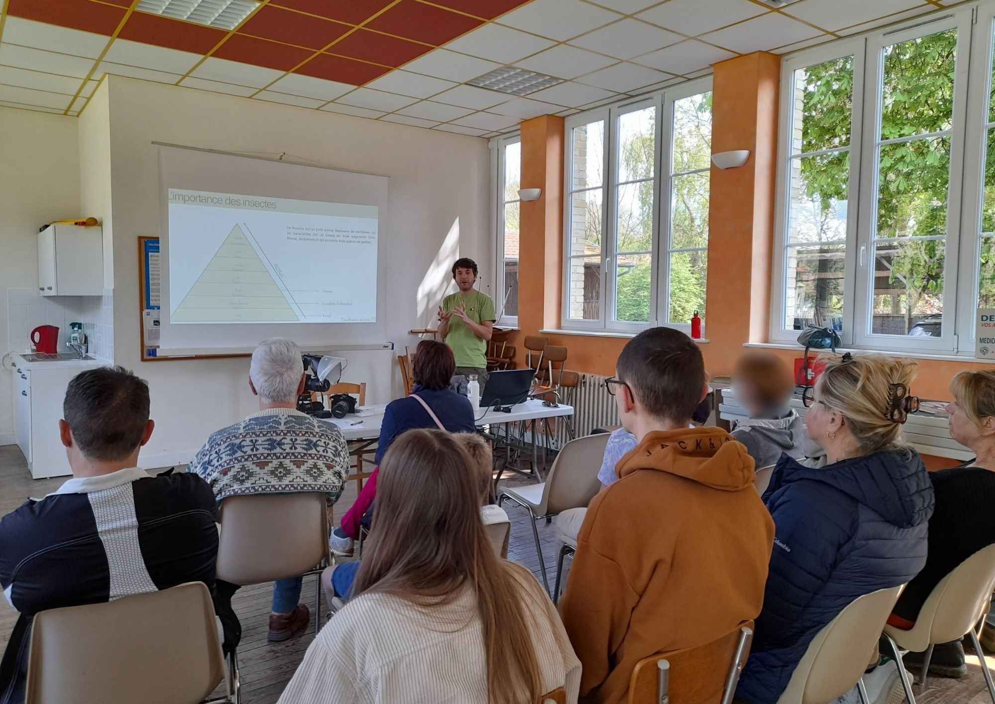 Sur l'image un animateur d'adresse à un public dans unes salle de classe