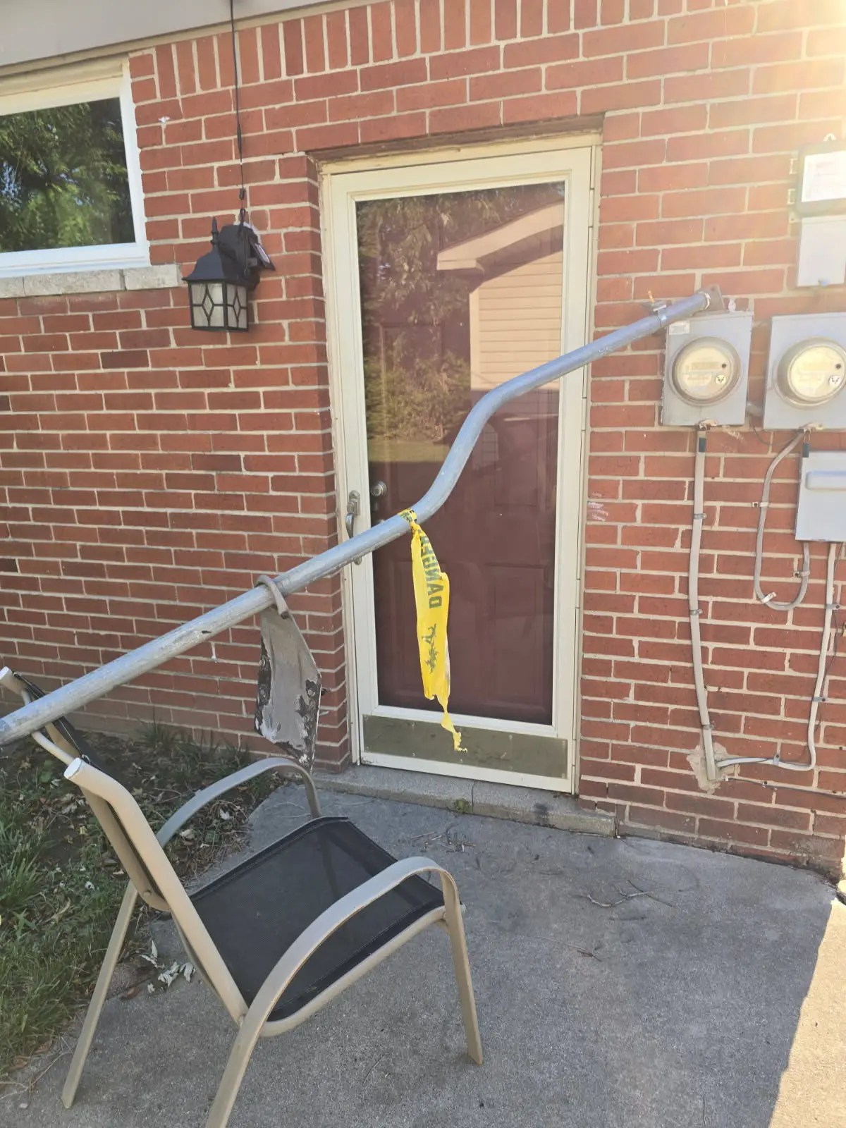 Bent electrical service riser pulled away from a brick home near electric meter sockets, showing storm damage requiring electrical repair in Metro Detroit, Michigan.