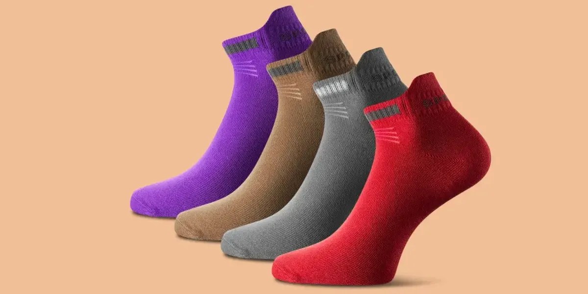 Color corrected image of socks in purple, brown, gray, and red on a beige background.