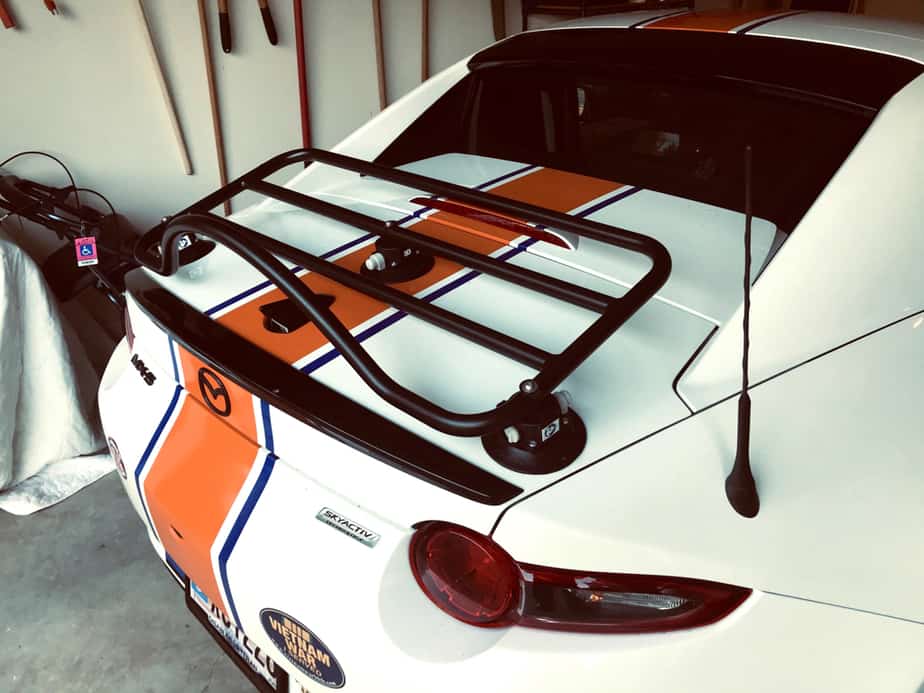 white mazda miata RF with an orange stripe and a revo-rack luggage rack fitted to the trunk